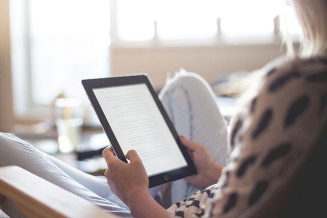 a person calmly sitting down while reading from a tablet